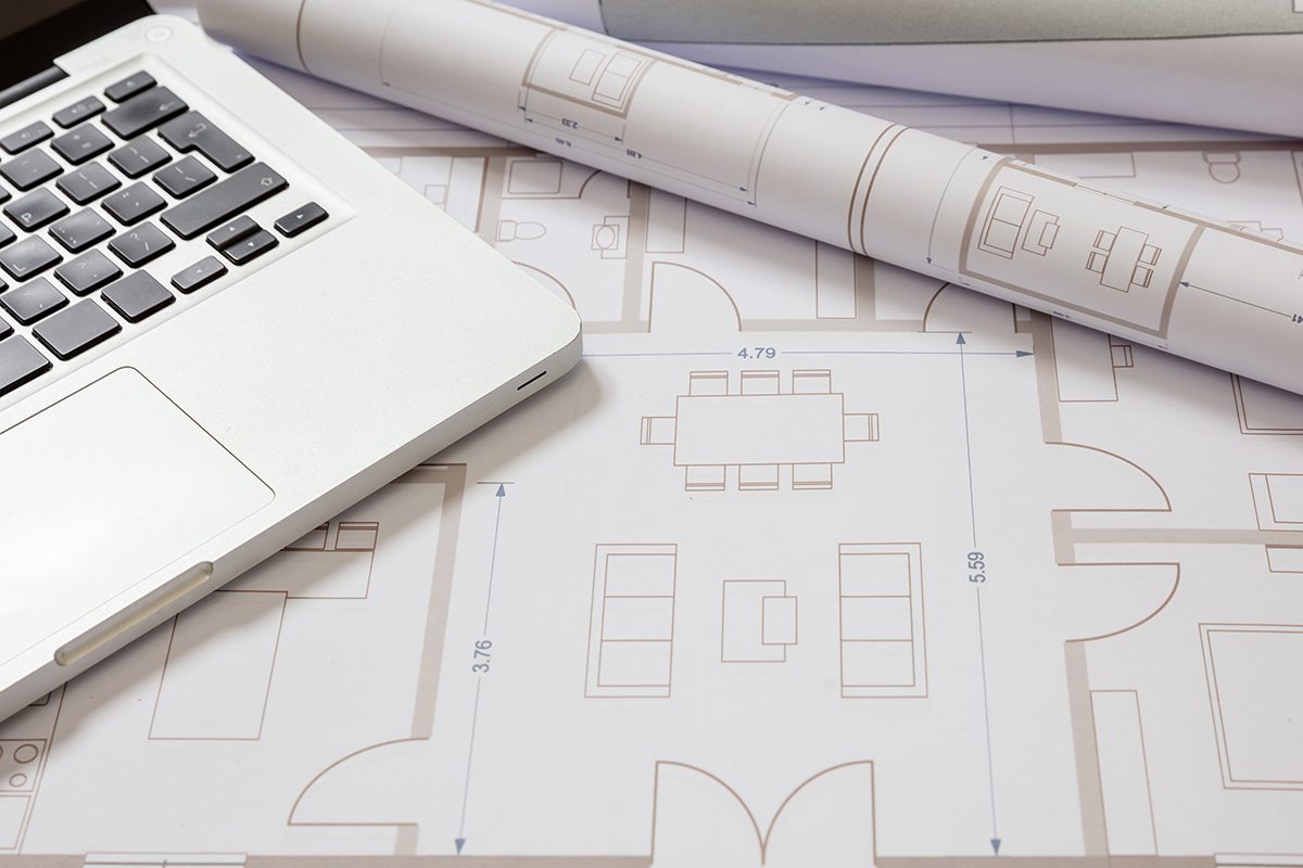 Architectural plans and a laptop on a work table